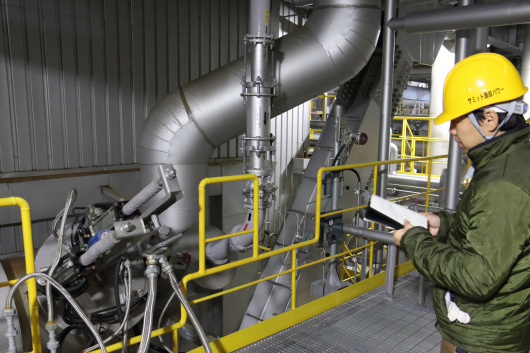 Mr. Tsuboi sketches the idea for an illustration while standing next to the boiler piping.